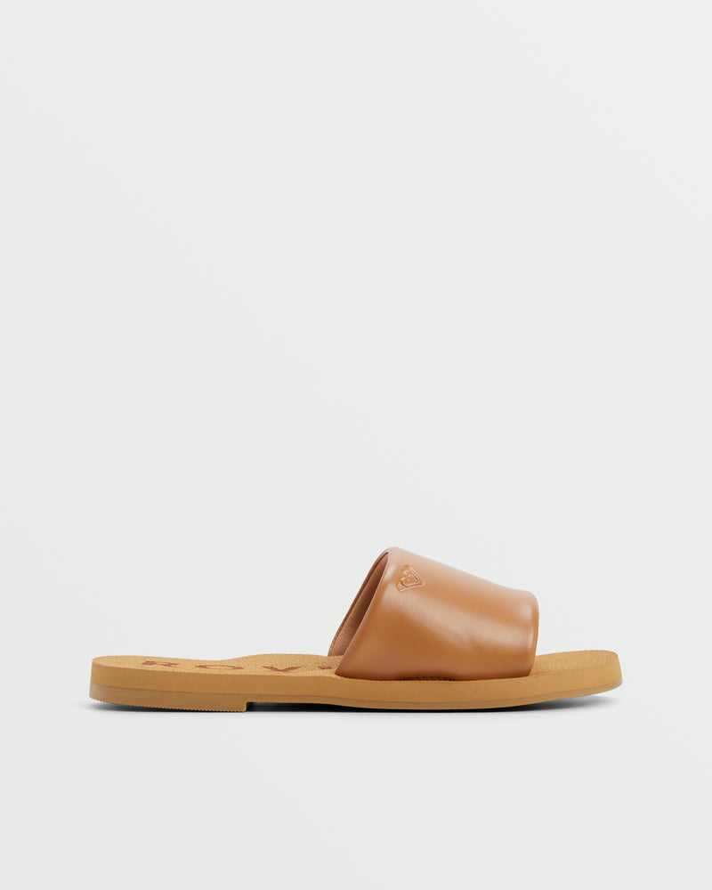 The ROXY Amalfi Coast Slide Sandal features a tan color, flat sole, and wide smooth leather strap across the top, shown against a plain white background.