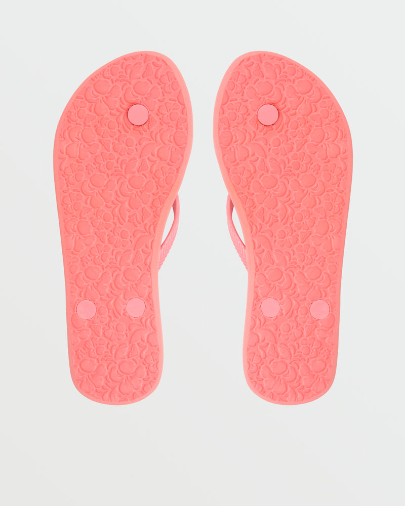 A pair of pink Roxy Antilles II Sandals shown from the bottom, featuring textured floral-patterned soles and three circular plugs on each comfortable sandal.