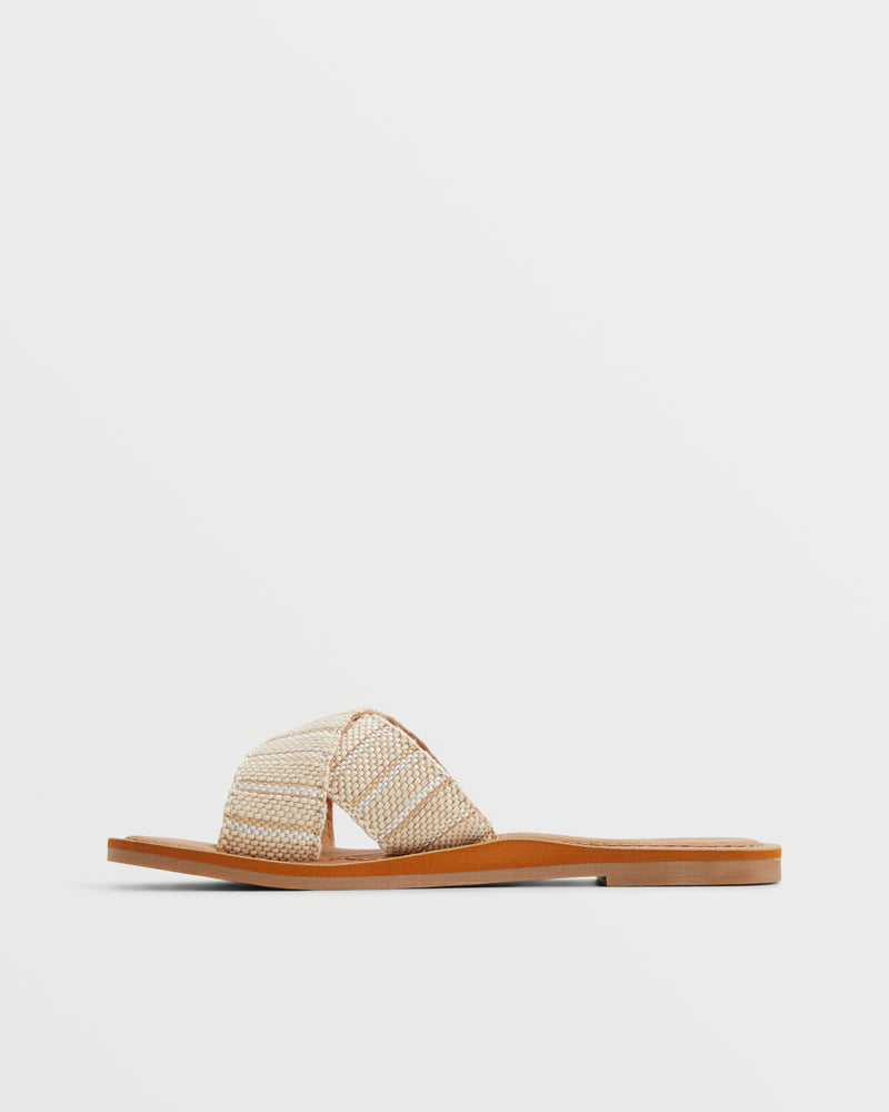 The Roxy Andreya Sandal features a tan sole and crisscrossed, woven beige straps, displayed in a side view against a white background.