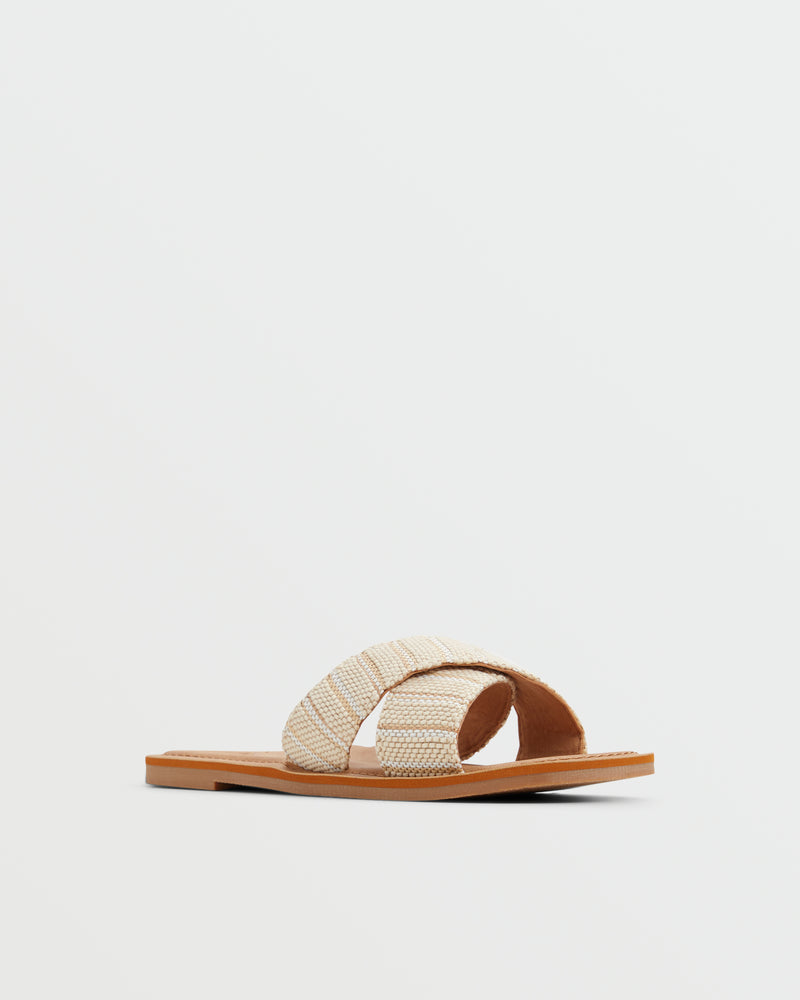The Roxy Andreya Sandal is a beige flat sandal featuring two wide, crisscrossed woven fabric straps and a tan sole, shown on a plain white background.