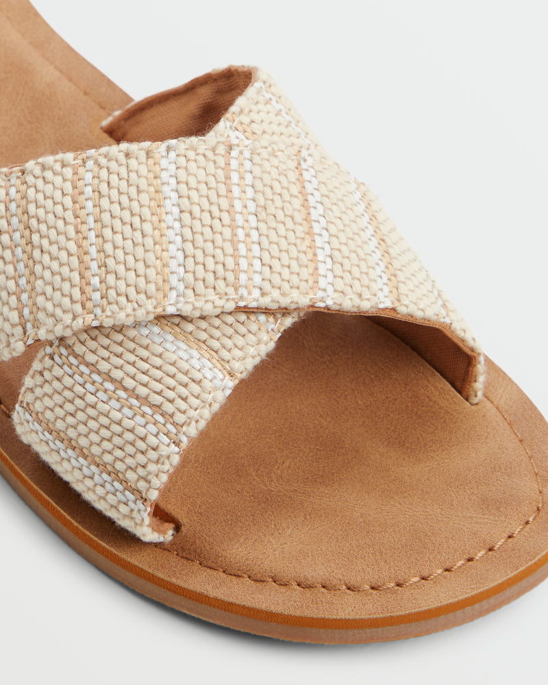 Close-up of the Roxy Andreya Sandal featuring a tan suede footbed, crisscrossed beige and white woven fabric straps, visible stitching, and a light brown sole.
