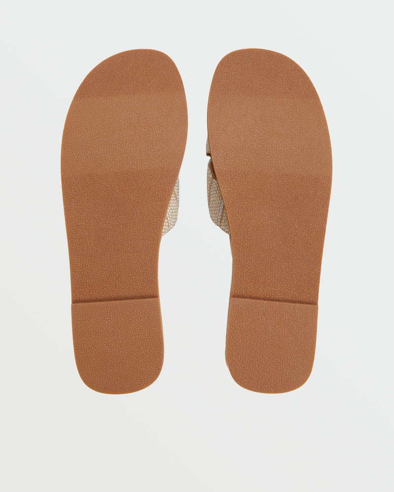 The Roxy Andreya Sandal is shown from the bottom, featuring flat brown soles with a slightly textured, rectangular design. The pair is positioned side by side against a white background.