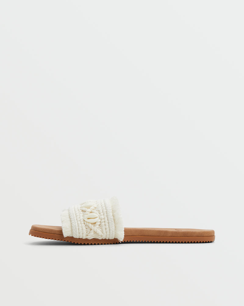 The Roxy Positano Sandal features a tan sole and a wide, textured white strap with crisscross details and decorative stitching, displayed on a plain white background.