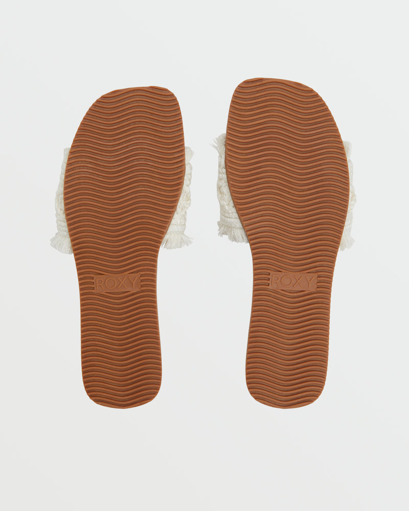 The Positano Sandal by Roxy is shown from the bottom, displaying brown textured soles with "ROXY" embossed on each foot and edges that reveal white woven material, all set against a plain white background.
