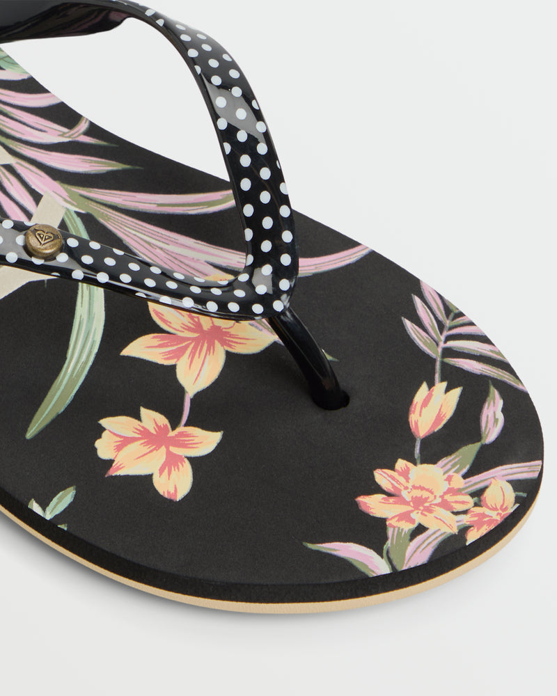 A close-up of the Roxy Portofino III Sandal shows its black base, white polka dot strap, and colorful floral footbed—making these sandals the perfect choice for sunny summer days.