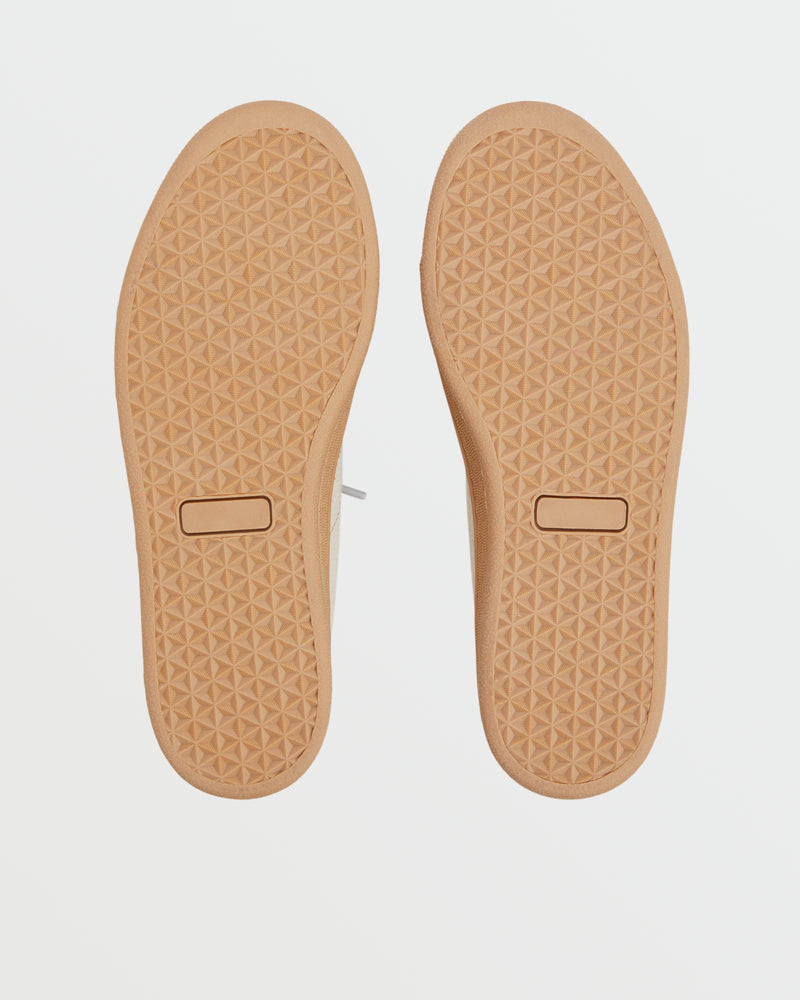 The Roxy Sunny Stroll Mule Sneaker features light brown soles with a diamond-shaped tread pattern and a rectangular mark near the heel, displayed against a white background.