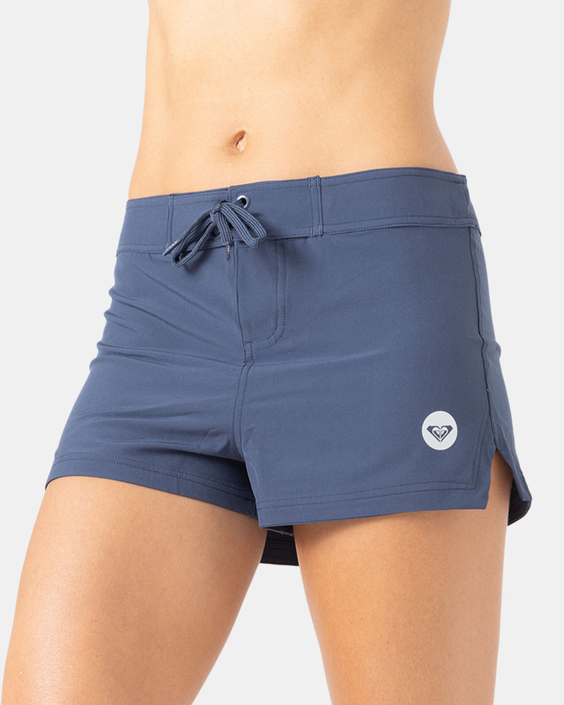 A person models the Roxy To Dye 2" Boardshort—blue, boardshort-style athletic shorts with a small white logo on the left leg—shown from waist to mid-thigh against a plain background.