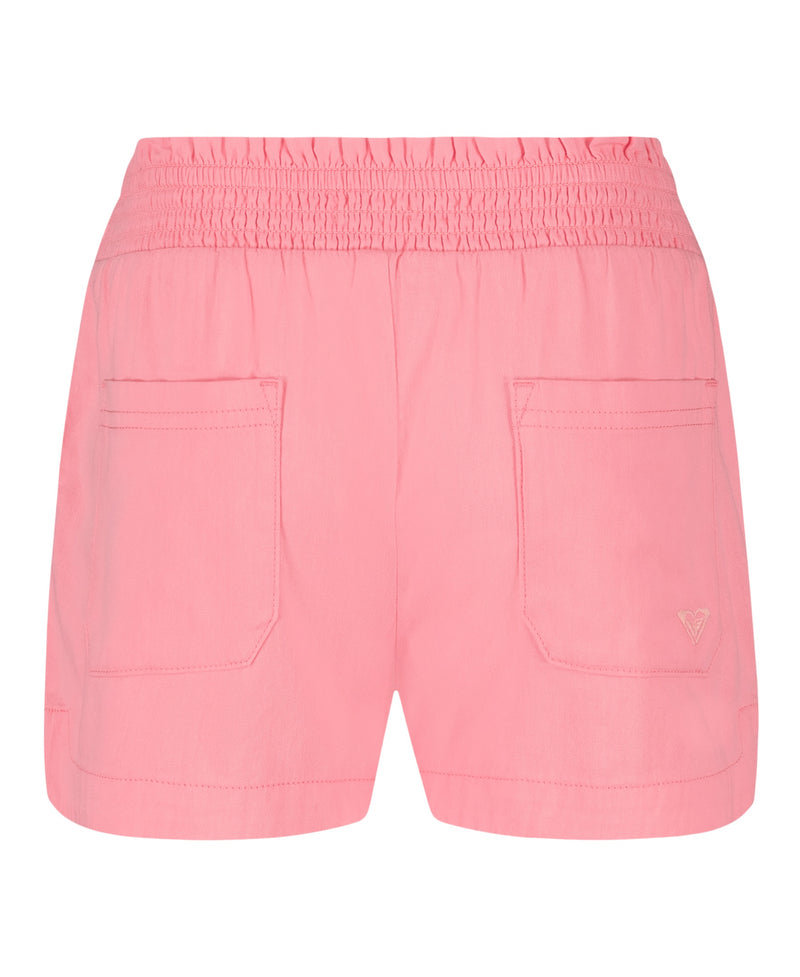 The Roxy Girls' Soleil Short features pink brushed twill, a smocked elastic waistband, two large front pockets, and a stitched logo—ideal for relaxed beachwear. Displayed against a white background.