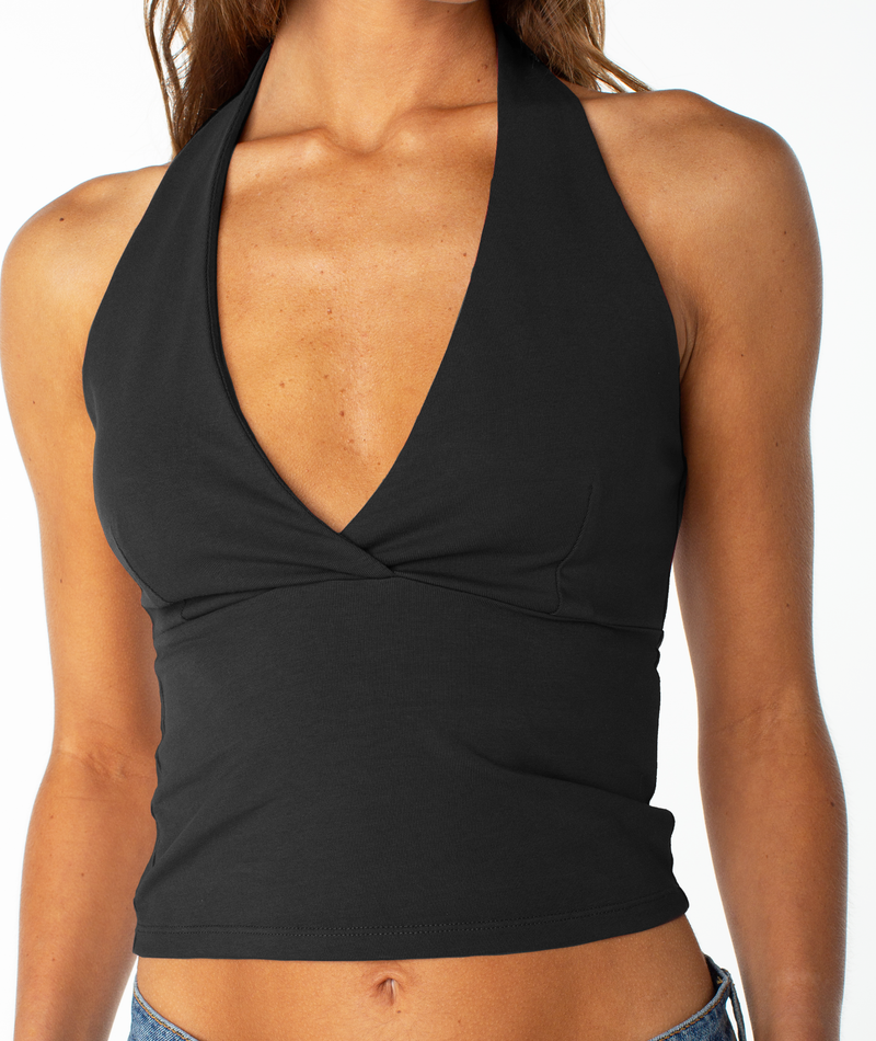 A woman wears the Roxy South Shore Halter Tank, a sleeveless black top with a deep V neckline, paired with blue jeans and shown from shoulders to waist against a plain background.
