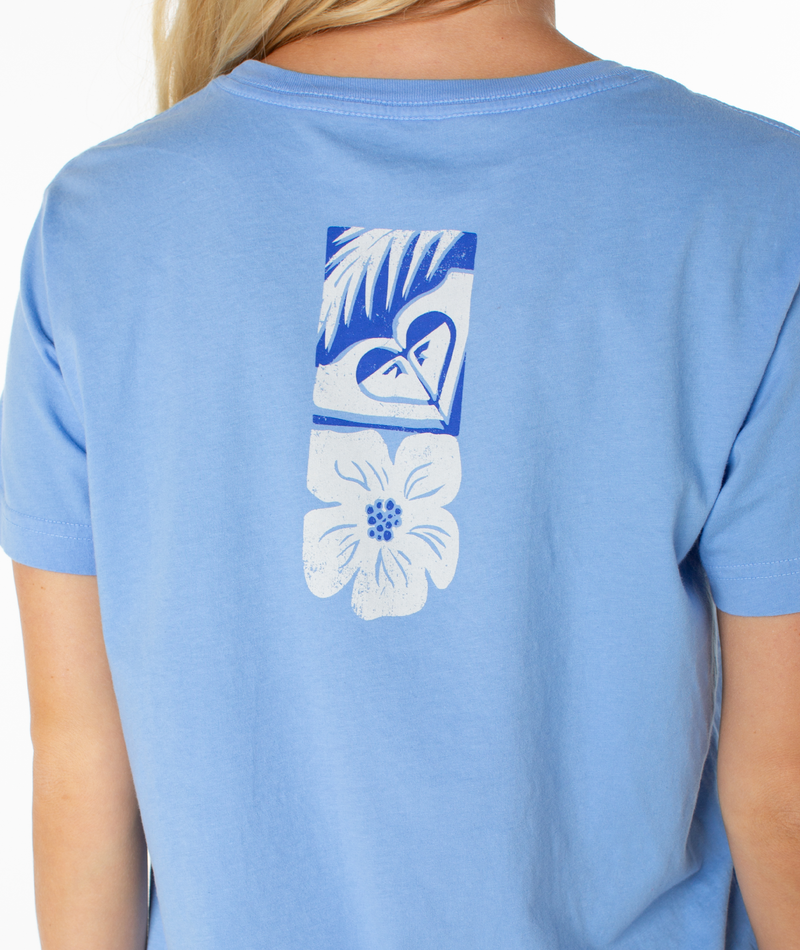 A person wearing the Roxy Beach Things Tee, a light blue top with a rectangular blue and white graphic of leaves, a heart, and a flower on the back.