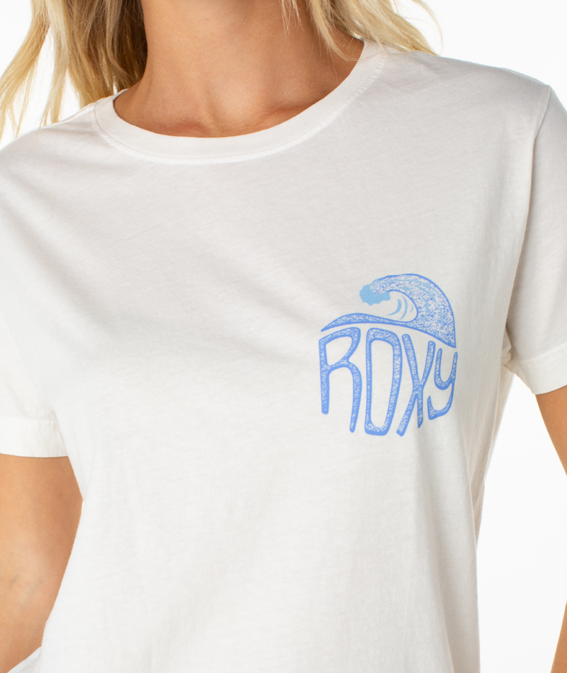 A woman is shown from the upper torso up, wearing the Roxy High Tides Tee—a white beachy top featuring a blue ROXY logo and wave graphic on the left chest.