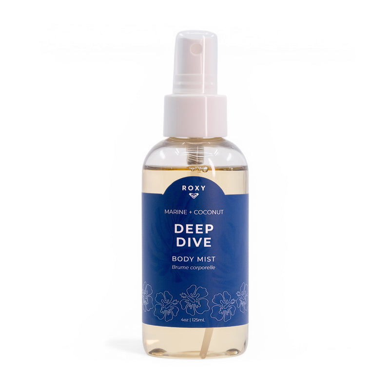 A clear spray bottle of Roxy Deep Dive Body Mist features a blue floral label and white cap, holding light yellow liquid with marine, coconut, and waterlily scents.