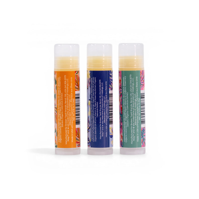 Three upright Roxy Lip Balm Set tubes—orange, blue, and green—feature tropical-themed labels and promise nourishing hydration with tropical flavors. Ingredient lists and barcodes are visible on a white background.