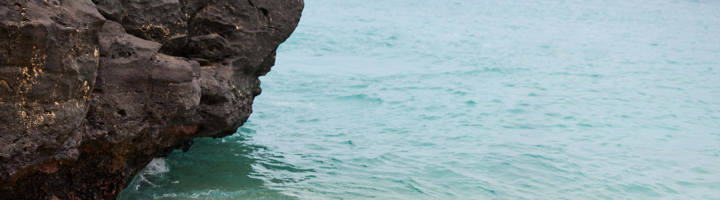 Rocks jutting into a body of water with a clear sky.