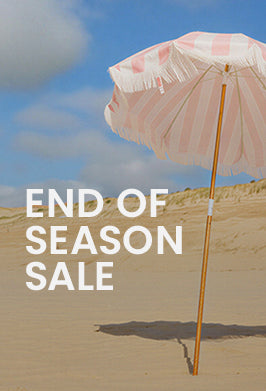 Pink beach umbrella on sand with 'End of Season Sale' text overlay