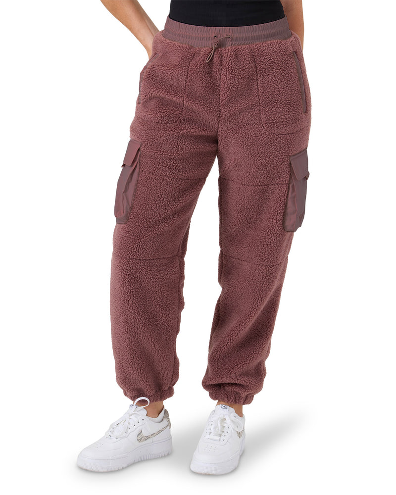 Plush mauve Roxy Rita Sherpa Jogger pants with elastic cuffs, a drawstring waistband, and side cargo pockets, paired with white sneakers.