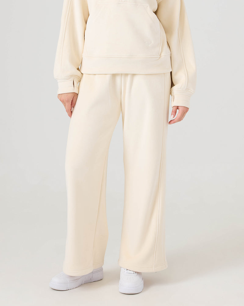 A person wears the Vivi Bonded Velour Pants by Roxy and a matching sweatshirt with white sneakers, standing against a plain light background. Their face is not visible.