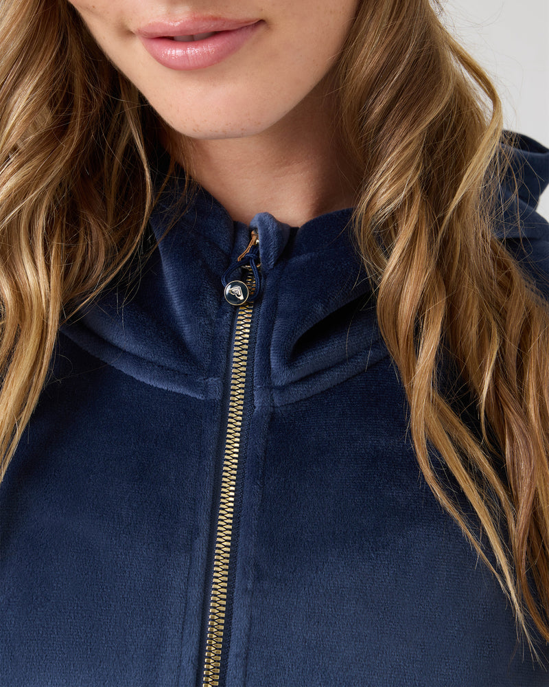 A woman with wavy blonde hair models the Vivi Bonded Pullover by Roxy in navy blue, with soft lighting highlighting its boxy fit and focusing on her mouth, hair, and upper torso.