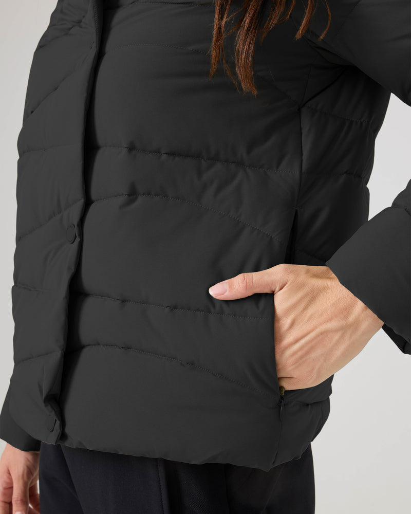 A person wears the Roxy Abby Quilted Puffer, a regular fit black quilted jacket with one hand in a side pocket. The photo shows only the torso and part of the arm, ideal for cool-weather style.