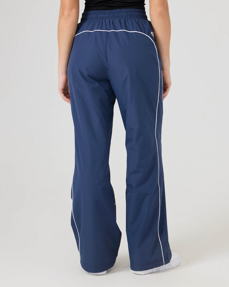 Person wearing Roxy Stevie Parachute Pants, shown from the back. These navy blue, wide-leg pants feature white piping and an adjustable waistband, set against a plain background.