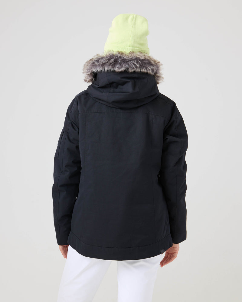 A person is shown from the back against a plain light background, wearing the Roxy Meade Jacket—a black women’s snowboard jacket featuring a faux fur-trimmed hood and insulated warmth—paired with a light yellow beanie and white pants.