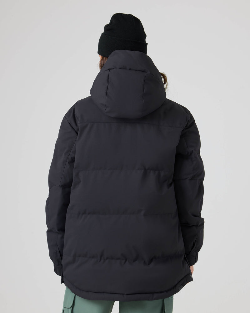 A person is shown from behind, standing against a plain light background with their hands at their sides, wearing a black beanie and the Roxy Jewelz Jacket, a women’s ski jacket featuring PrimaLoft insulation and a hood.