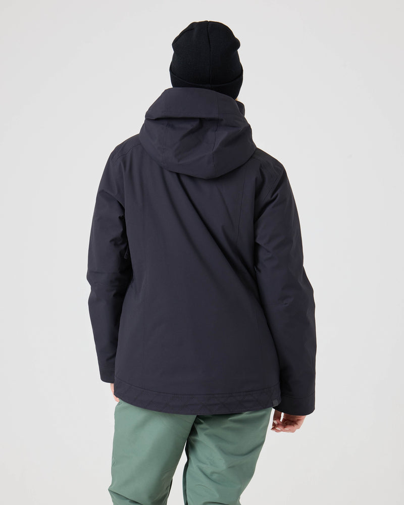 A person wearing the Roxy Billie Jacket, green pants, and a black beanie stands facing away against a plain white background.