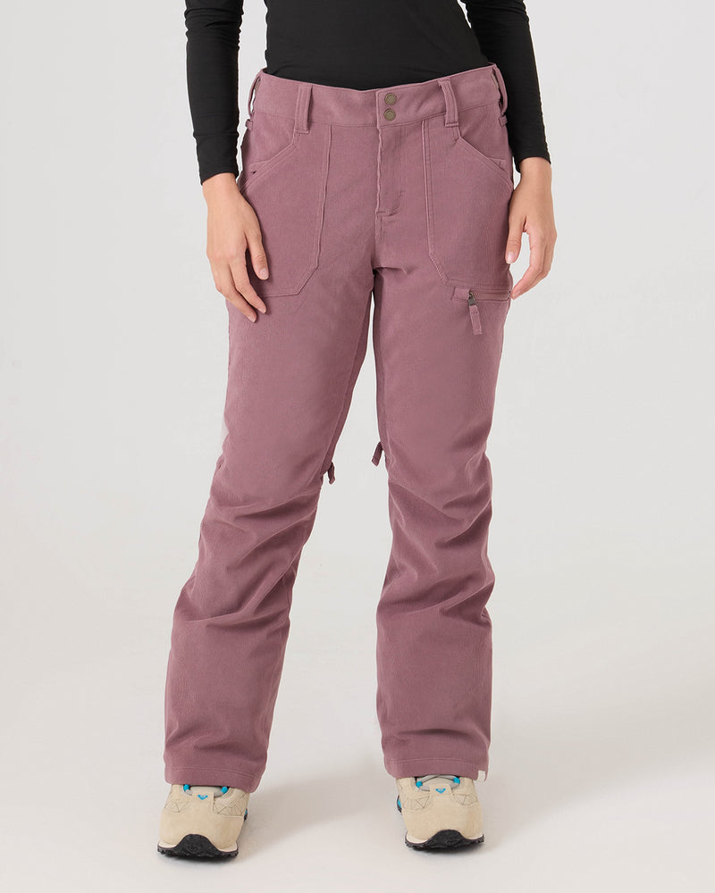 A person wearing the Roxy Nadia Pants in Rose Taupe, styled with a tailored fit, along with a black long-sleeve top and beige sneakers stands against a plain light background. The image is cropped from the shoulders down.