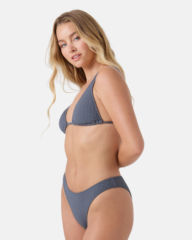 A woman with long blonde hair poses against a white background, wearing the Roxy Haleiwa Built Up Triangle Bikini Top in textured gray recycled stretch fabric, looking over her shoulder at the camera.