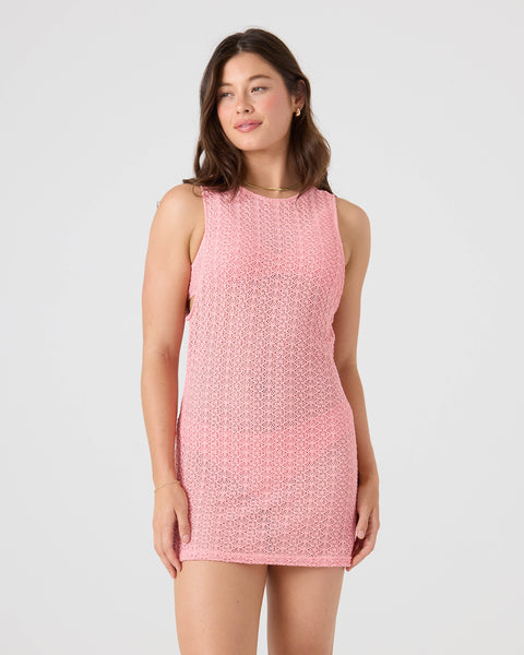 A woman with long brown hair wears the Roxy Crochet Cover Up Dress in light pink, standing against a plain white background and looking slightly to the side with a relaxed expression.