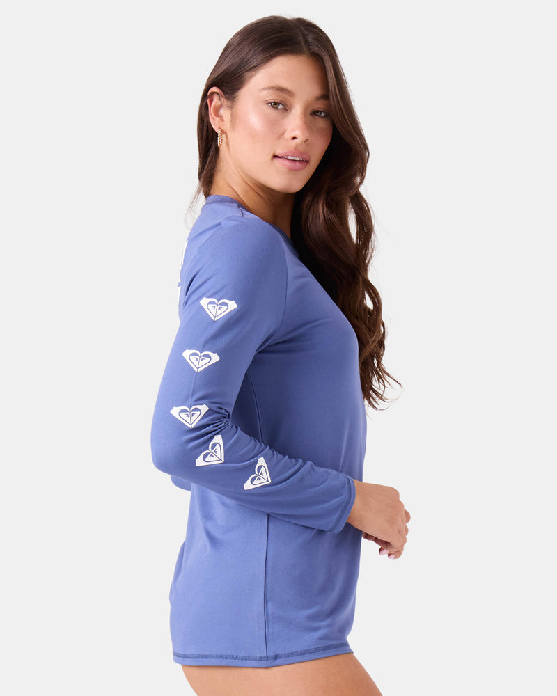 A person wears a periwinkle Roxy Surf City Warm Shirt featuring a repeating mountain and wave logo down the length of the right sleeve.