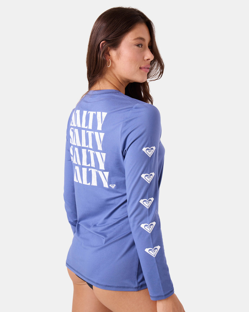 Roxy Surf City Warm Shirt, a long-sleeved purple rashguard with SALTY printed repeatedly on the back and a series of heart-shaped logos down the left sleeve.