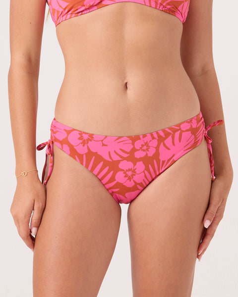 A person models the Roxy Sun Chasers Hipster Lace Full Bikini Bottom in Pink Combo, featuring side ties and made from recycled nylon. Only the torso and upper legs are shown, set against a plain light background.