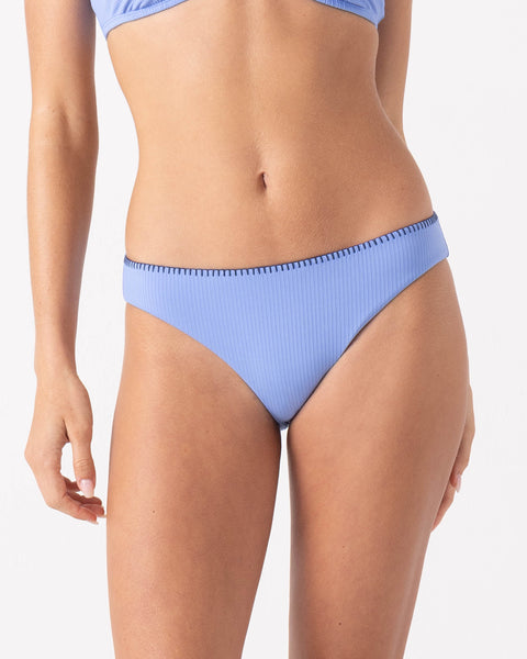 A woman wears the Roxy Loop Me In Hipster Full Bikini Bottom in Cornflower with black stitching and a ribbed texture, shown from midriff to upper thighs against a plain white background.