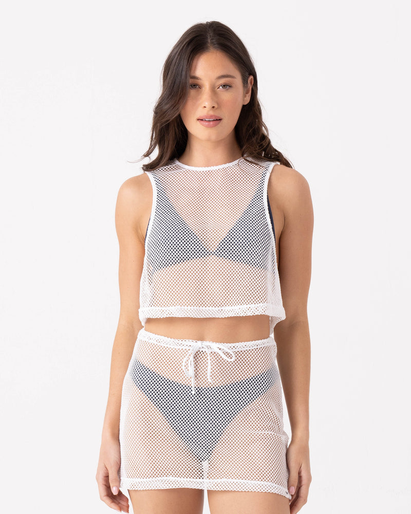 A woman poses against a white background in the Roxy Don't Mesh With Me Crop Top Cover Up in Egret, styled over a black bikini with its matching high-waisted loose-fit mesh skirt featuring a drawstring.