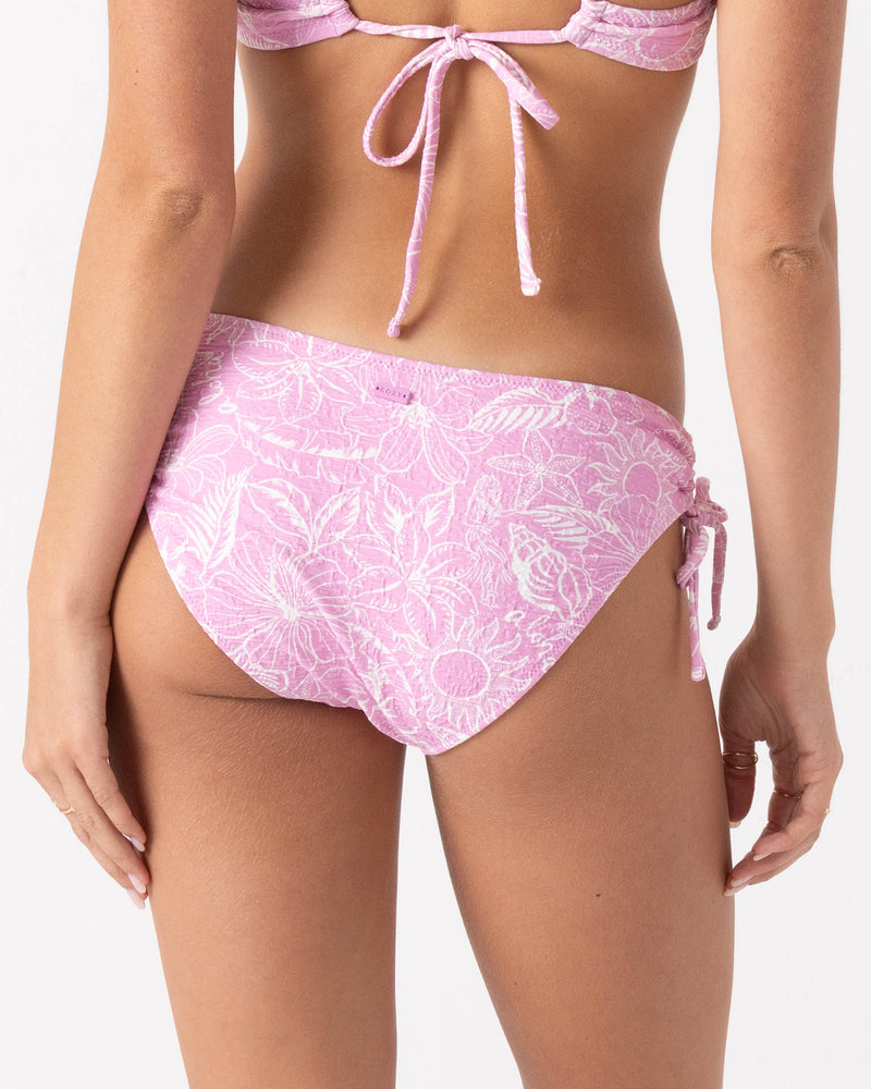 Woman seen from the back wearing the Roxy Bora Bora Hipster Lace Full Bikini Bottom in pink floral with adjustable tie sides; matching bikini top partially visible, showing a back tie.