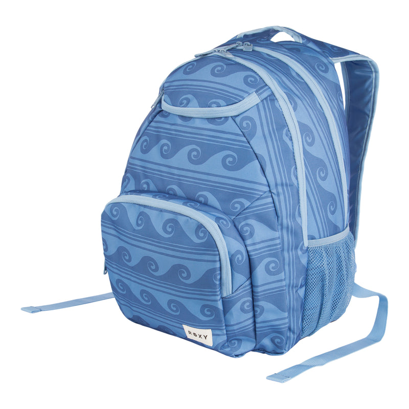 The ROXY Shadow Swell Backpack features a blue color with light blue wave patterns, front and side pockets, a mesh side panel, and a small white rectangular label on the bottom front pocket.