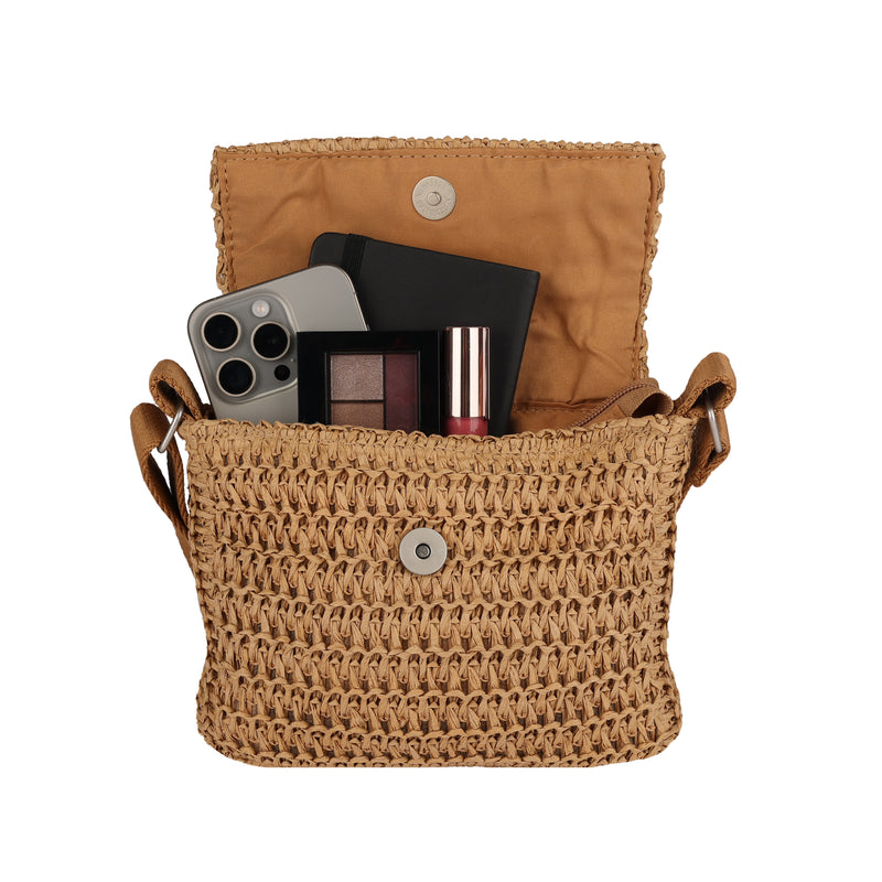 The Roxy Spotless Sunnies Crossbody Bag in tan sits open, flaunting its flapover design while showcasing a smartphone, notebook, eyeshadow palette, and lipstick inside.