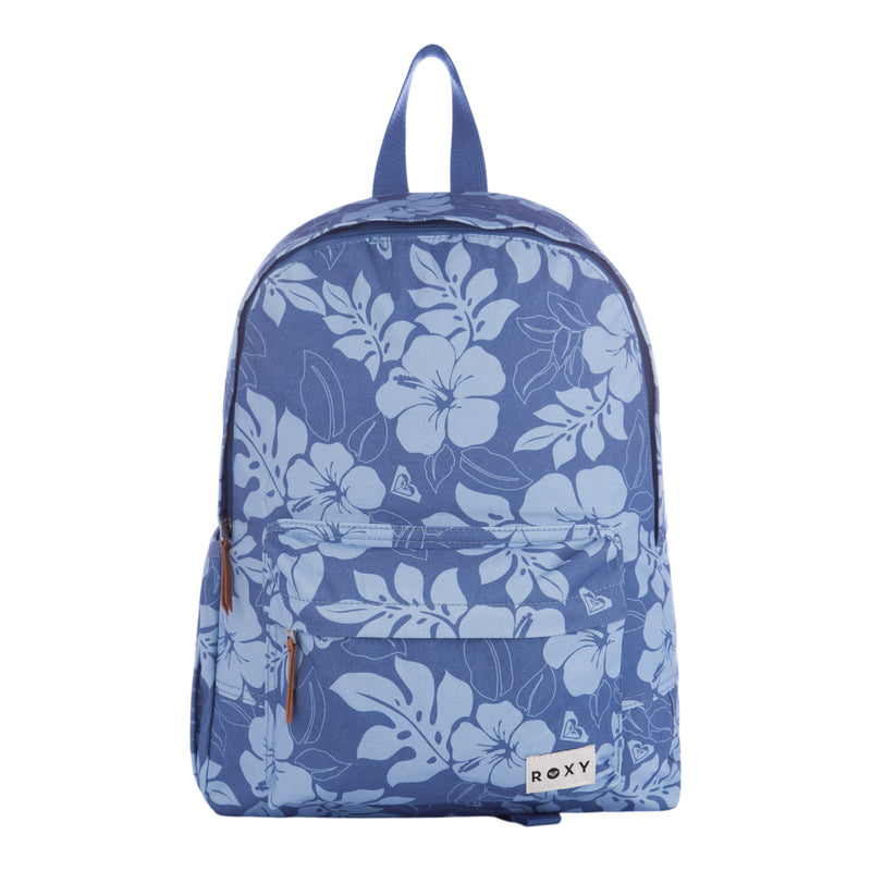 The Roxy Sugar Baby Canvas Backpack features a blue canvas with a white floral pattern, a front zipper pocket with brown zipper pulls, and a top handle. The Roxy brand label is displayed on the lower pocket.