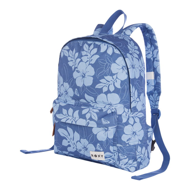 The Roxy Sugar Baby Canvas Backpack features a blue background with a white floral pattern, one spacious main compartment, and a front zippered pocket. It has adjustable shoulder straps and a small white Roxy logo patch on the front. The backpack is shown standing upright against a white background.