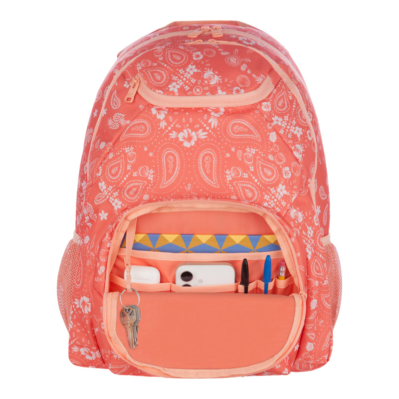 A coral pink patterned Roxy Shadow Swell Backpack with its front pocket open, neatly displaying a phone, pens, pencils, a key on a keyring, and a triangular-patterned notebook inside.