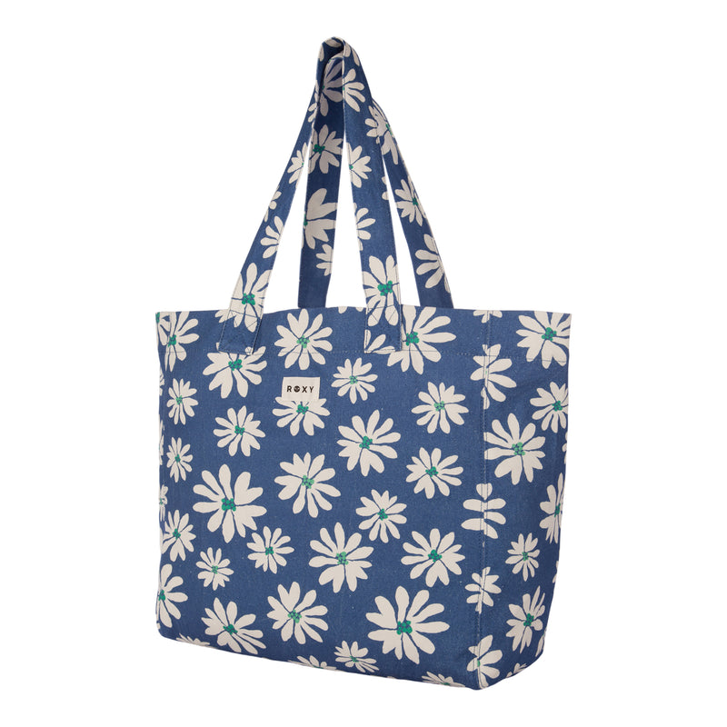 The Roxy Anti Bad Vibes Tote Bag in blue features a white daisy flower print, two sturdy handles, and a small rectangular Roxy label on the front. Made from recycled cotton, this stylish tote bag offers an eco-friendly accent to your everyday look.
