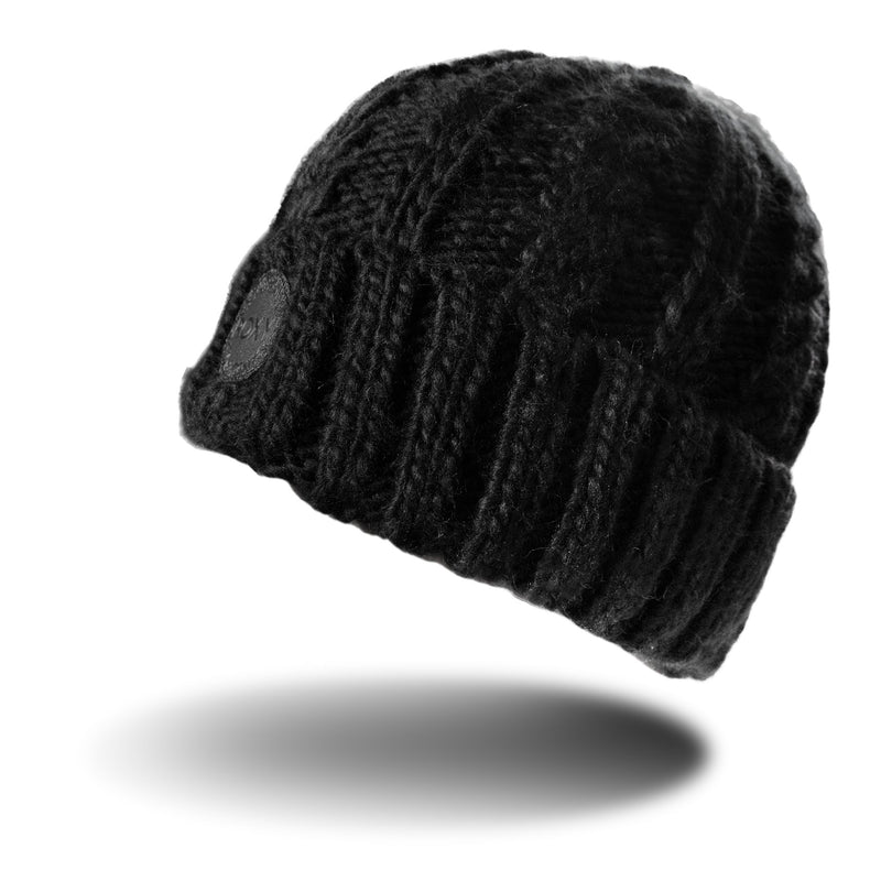 The Tram Beanie by Roxy features a black cable knit design with a textured pattern and a small round patch on the front, displayed floating above a white background with a soft shadow beneath it. This stylish women’s beanie from Roxy perfectly blends fashion and warmth.