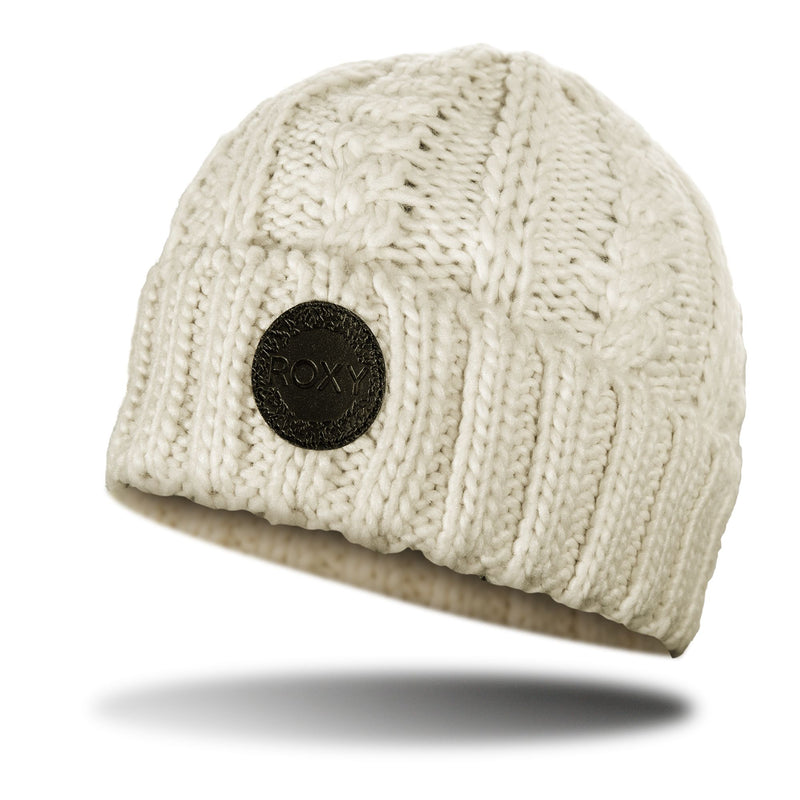 The Roxy Tram Beanie is a cream-colored, fleece-lined cable knit beanie featuring a stylish cable pattern and a round black ROXY logo patch on the front, shown floating above a shadow on a white background—ideal for effortlessly elevating any women’s beanie collection.