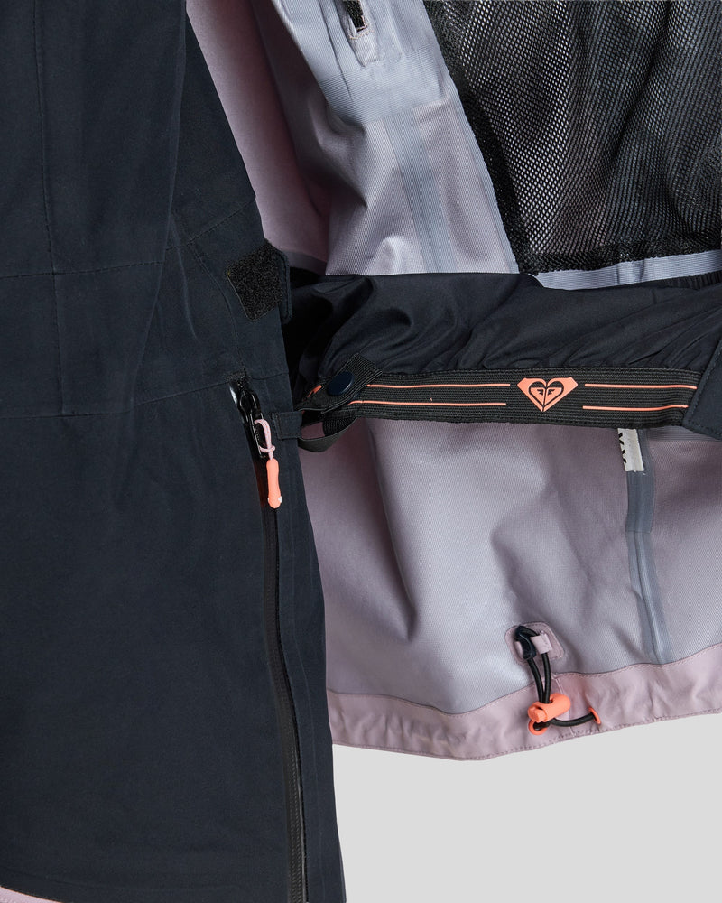 Close-up of a partially unzipped Roxy Gore-Tex Lunalite Jacket revealing interior features such as a mesh pocket, an orange clip, and a logo on the inner elastic band. The light purple lining is also visible.