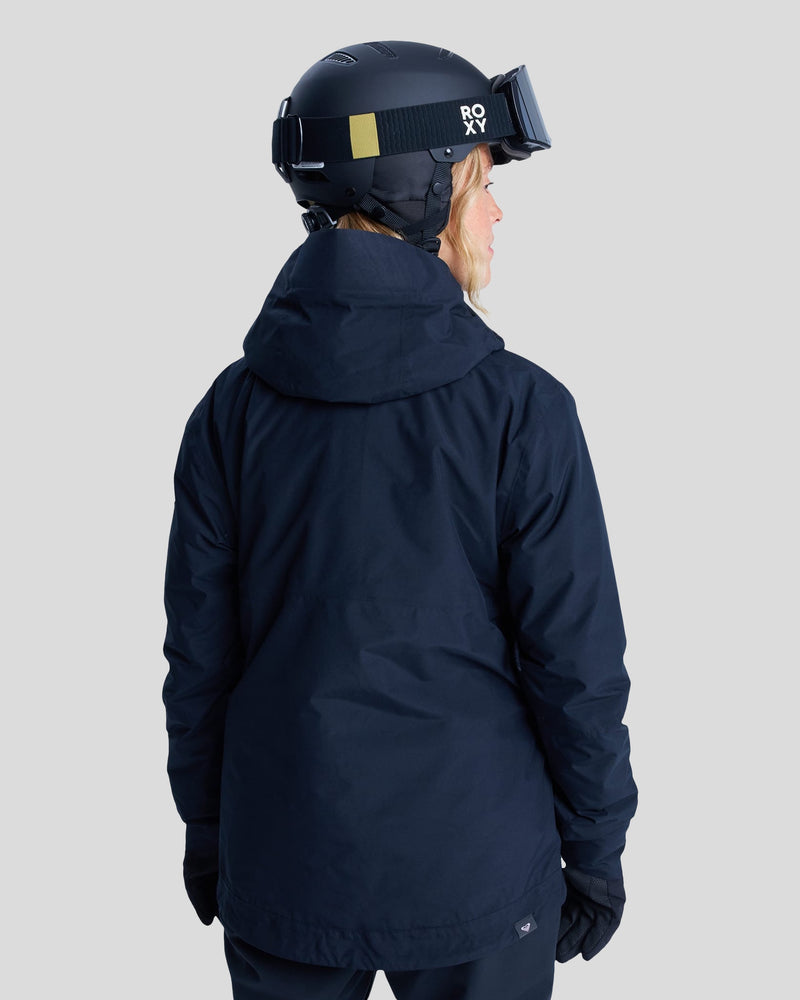 A person in a black helmet, black gloves, and a dark jacket—possibly the Roxy Gore-Tex Stormday Jacket—stands facing away from the camera against a plain gray background.
