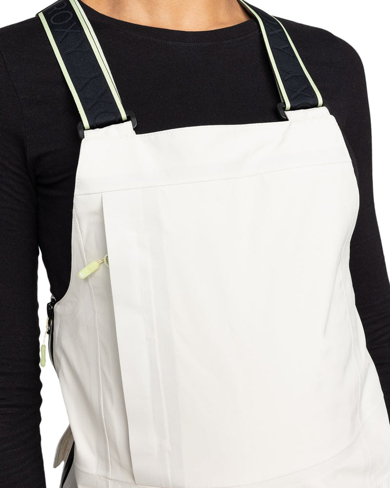 A person wearing a black long-sleeve shirt and Roxy Gore-Tex 3L Lunalite Bib—white waterproof women’s snow bib-style overalls featuring black and light green straps. Only the upper torso is visible.
