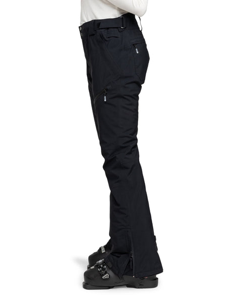 A person wearing black Gore-Tex Spridle Pants by Roxy and black ski boots stands in profile against a white background.