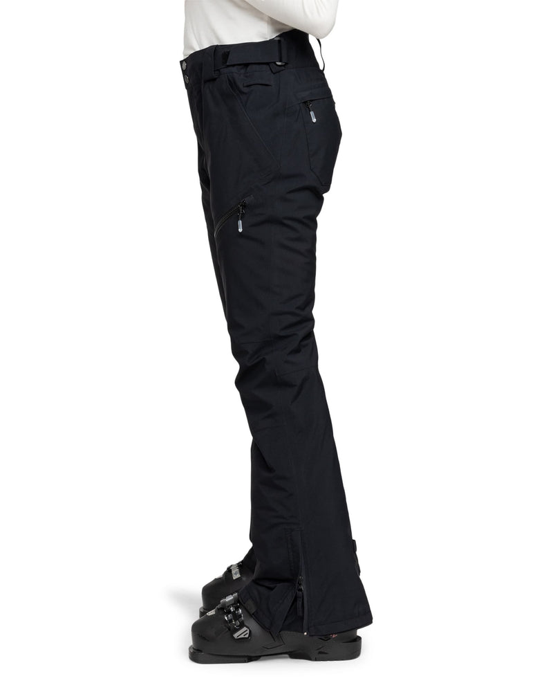 A person wearing black Gore-Tex Spridle Pants by Roxy and black ski boots stands in profile against a white background.
