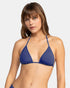 A woman with straight light brown hair wears the Roxy Sd Beach Classics Tiki Tri bikini top in blue, standing against a plain light background and looking at the camera with a neutral expression.